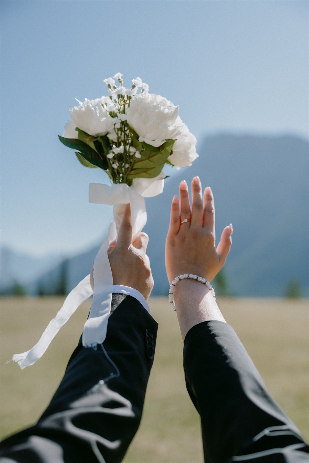 Sample photo: a bouquet of white roses tied with a satin ribbon, held up against a blue sky.